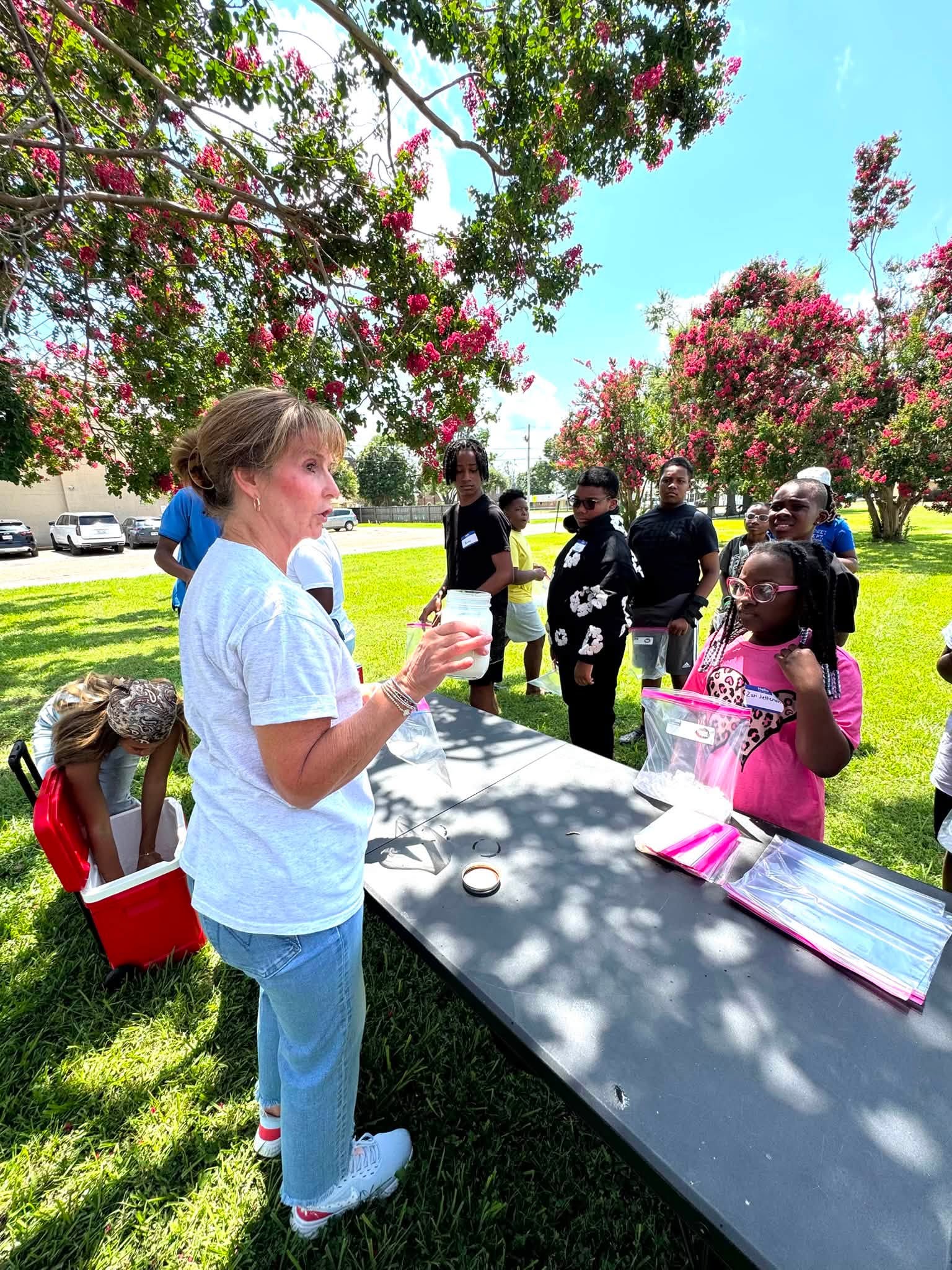 A woman talking to a group of kids outside.